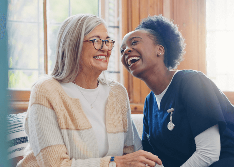 Smiling nurse with elderly woman, showcasing compassionate senior care in a cozy home setting.