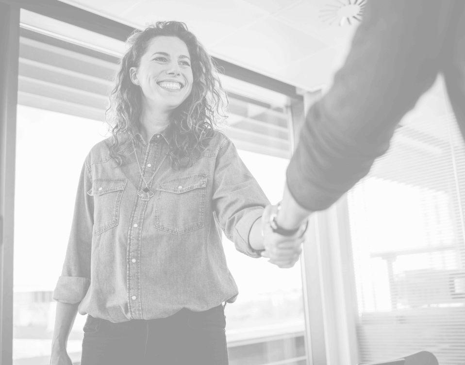 Two professionals shaking hands in an office, representing the Trusted Talent referral program